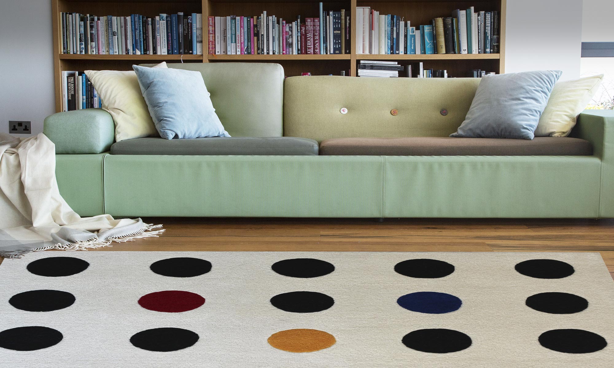 a polka dot rug displayed on a wooden floor with a green couch