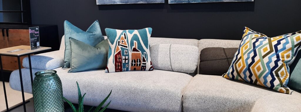 Handtufted scatter cushions on a light grey couch within a setting.