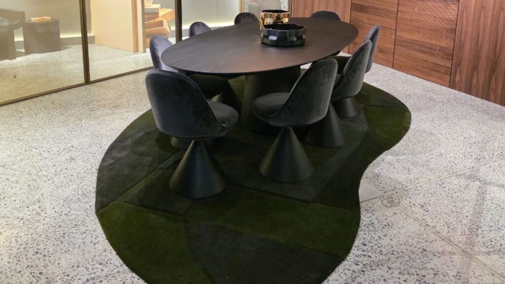 Oval rug in various shades of green placed underneath a boardroom table