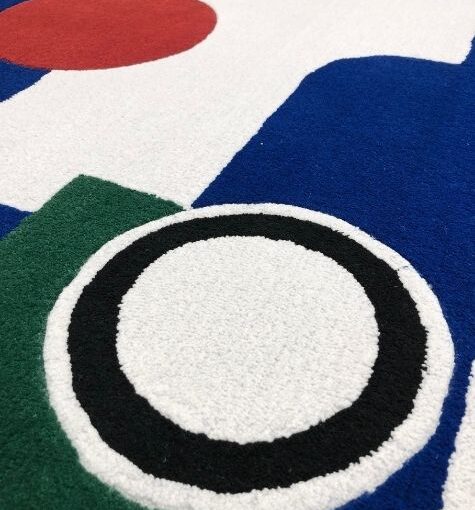 handtufted rug in white, blues, reds, and greens with circular design elements. Designed by Renee Rossouw