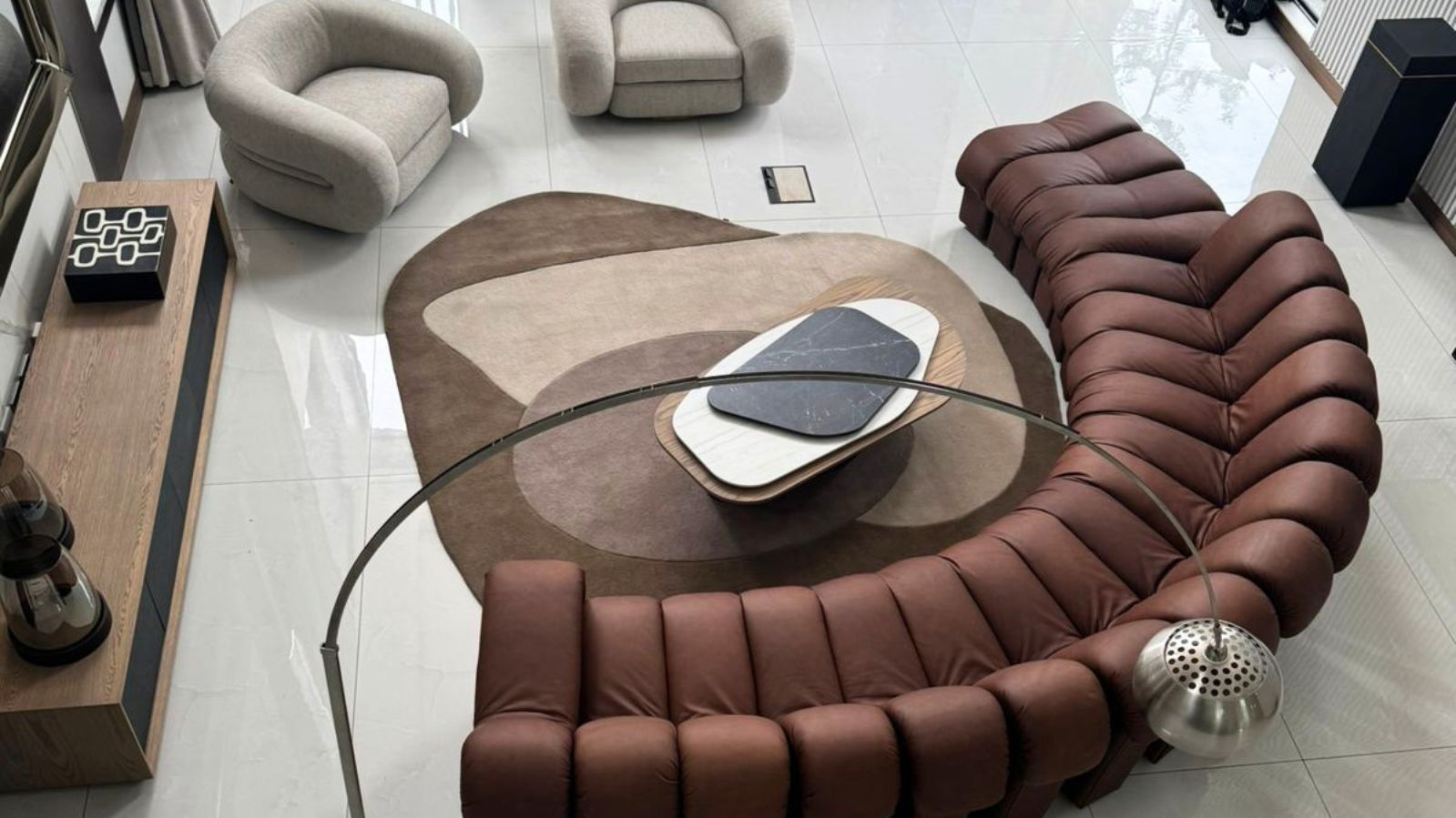 Bespoke organic shaped rugs anchoring minimalist furniture in an open-plan living room.